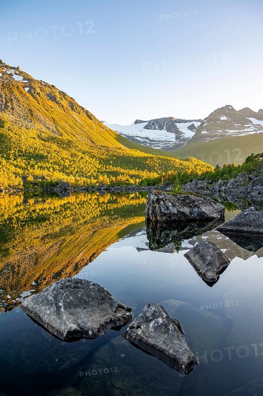 Picturesque mountain landscape in the Innerdalen high valley, mountain peaks reflected in Lake Innerdalsvatna, in the evening light at sunset, Trollheimen Mountain Area, Sunndal, Møre og Romsdal, Norway
