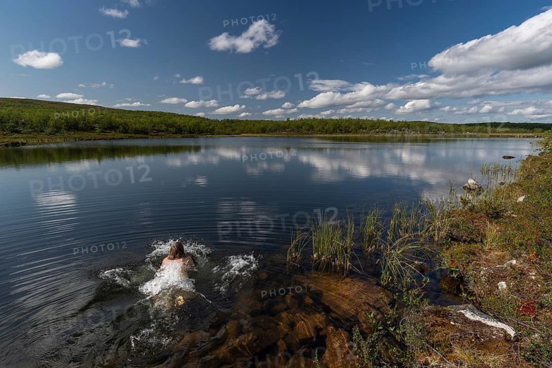 Woman jumping into a lake, near Utsjoki or Ohcejohka, Lapland, Finland