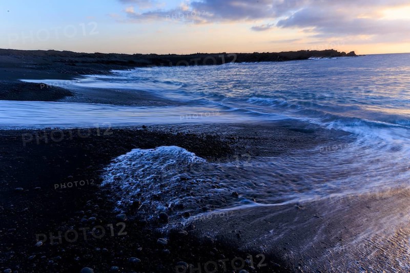 Lanzarote, Canary Islands, Spain, Europe, Los Hervideros, waves break gently on the beach during a quiet sunset, the sky is covered with clouds