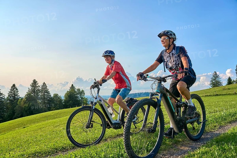 Two senior girlfriends have fun during a e-bike cycling tour in the Allgau Alps near Oberstaufen, Bavaria, Germany