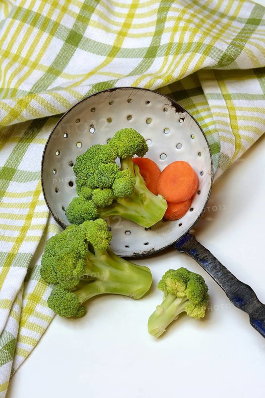 Broccoli in sieve trowel and carrot slices, Brassica oleracea var. italica