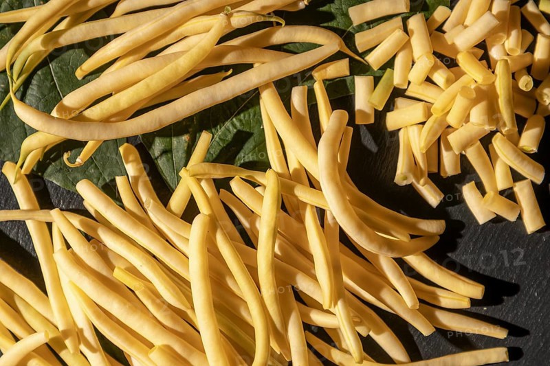 Sliced and whole yellow beans on leaves