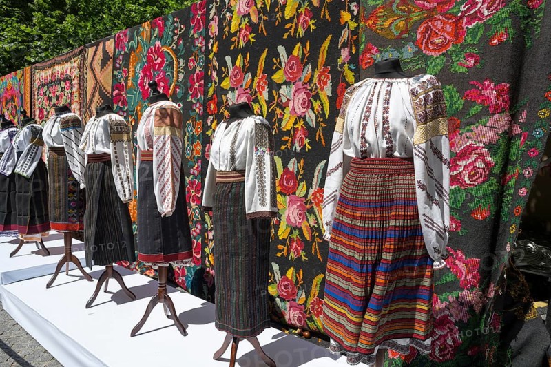 Exhibition of traditional clothing with intricate embroidery in front of floral wallpaper, folklore festival, Chisinau, Chisinau, Chisinau, Republic of Moldova, Moldova, Eastern Europe