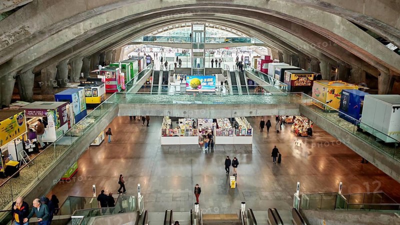 Panorama of large, modern station concourse with concrete walls and people on escalators, Oriente bus station, Lisbon, Portugal