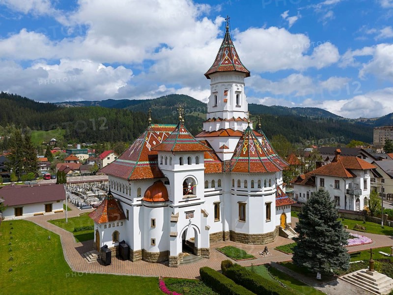Orthodox church with decorative roof in a mountainous landscape under blue sky with clouds, aerial view, Assumption of the Blessed Virgin Orthodox Church, Câmpulung Moldovenesc, Campulung Moldovenesc, Kimpolung, Suceava County, Bukovina Region, Romania