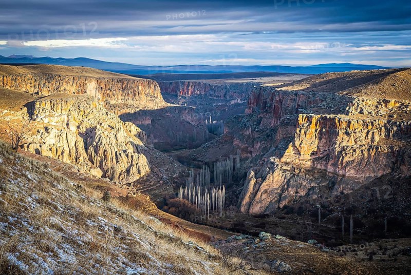 Panoramic view to Ihalra valley canyons dunring the sunrise in winter with dramatic cloudy sky. Hking and travel. Turkey