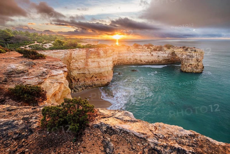 Arco de Albandeira spans the ocean cove at Praia de Albandeira beach in Algarve, Portugal, during a colorful sunrise