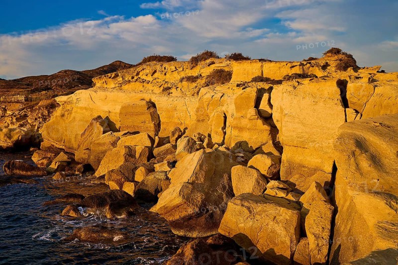 Rough rocky coast in golden light on a sunny day by the sea, Aspragremna, White Cliffs, Mavorspilia Beach, Kimolos Island, Kimolos, Cyclades, Greek Islands, Greece