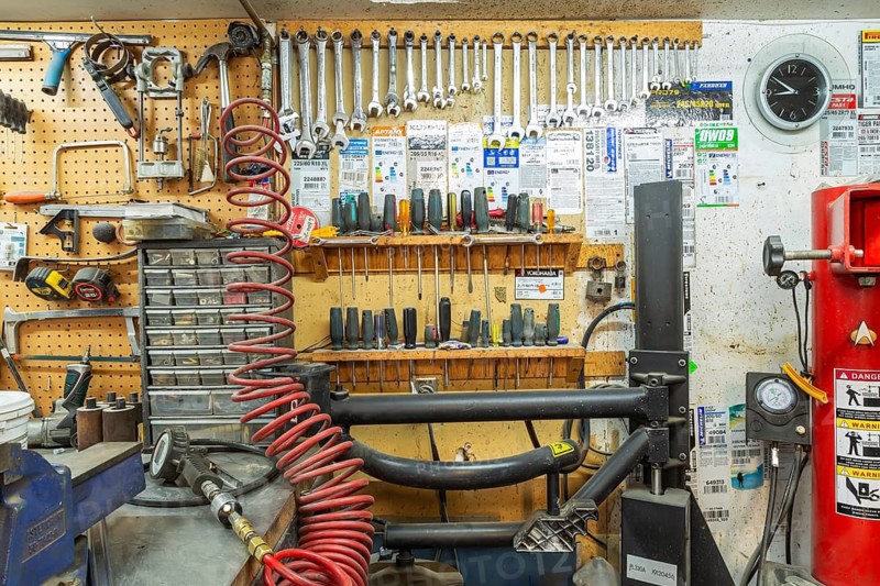 Parts drawers, various hand tools including wrenches, screwdrivers, hammer arranged on shelves and hanging rack inside home garage workshop, Quebec, Canada
