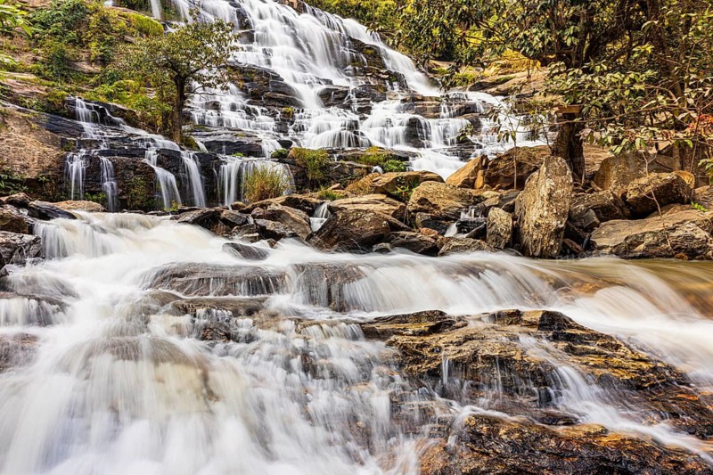 Mae Ya waterfall with cascading flowing water surrounded by lush tropical vegetation, near Doi Inthanon National Park, Chiang Mai Province, Thailand