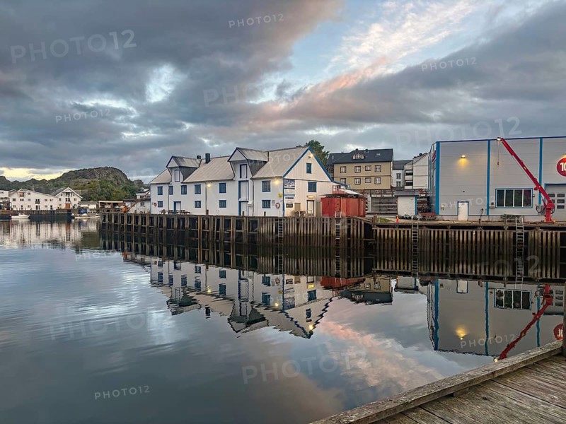 Quiet harbor with white wooden houses and calm water reflections at dusk, midnight, cable vag, fishing, Lofoten, Nordland, Norway