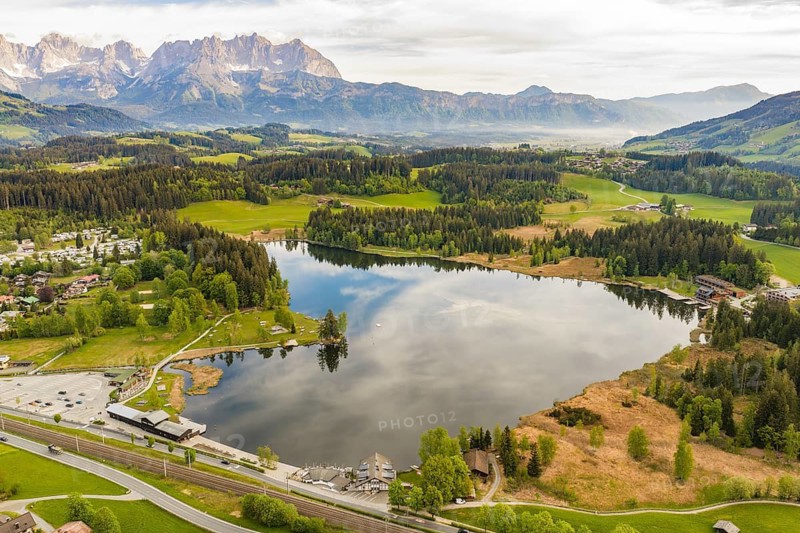 Large lake surrounded by a vast mountain landscape with lush greenery and forests, Schwarzsee circular trail, Kitzbühel, Austria