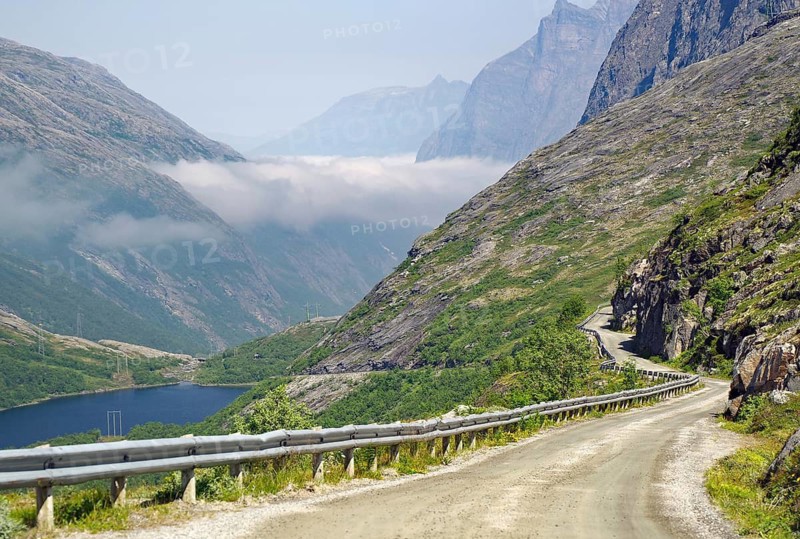 A winding mountain road leads through a rocky, foggy landscape, Aursjövegen, More og Romsdal, Norway