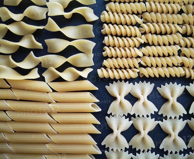 The texture of four types of pasta: tagliatelle, farfalle, penne and fusilli.Close-up. Top view. Horizontal