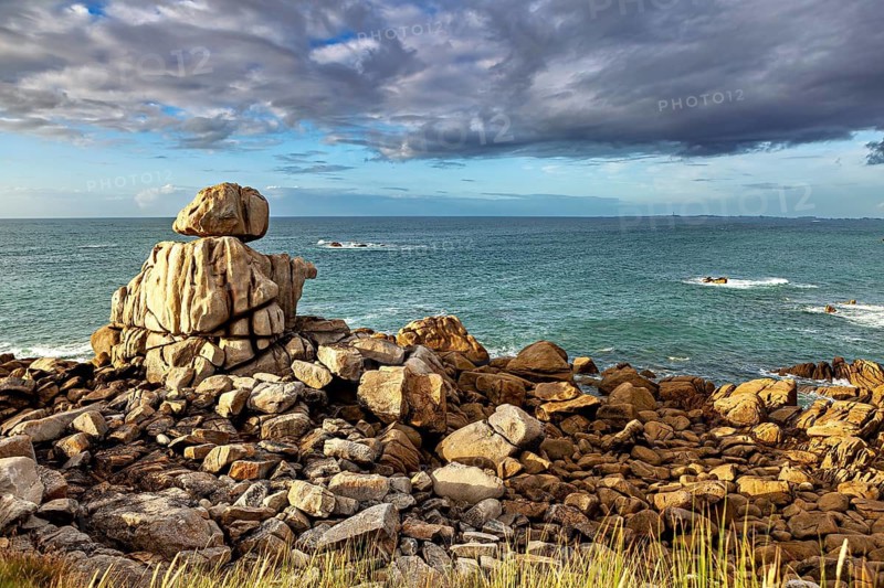 Rocks off the coast in the light of a dramatic sky in the late afternoon, The coastal landscape near Cleder in Brittany