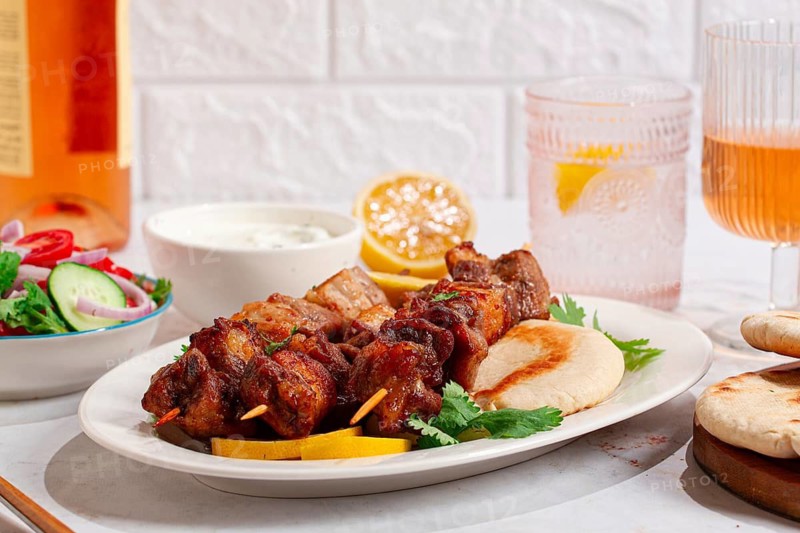 Souvlaki, a Greek dish, grilled meat shish kebab, on a plate with flatbreads, and lemon slices, grilled meat shish kebab, served with lavash, salad and drinks where there are no people