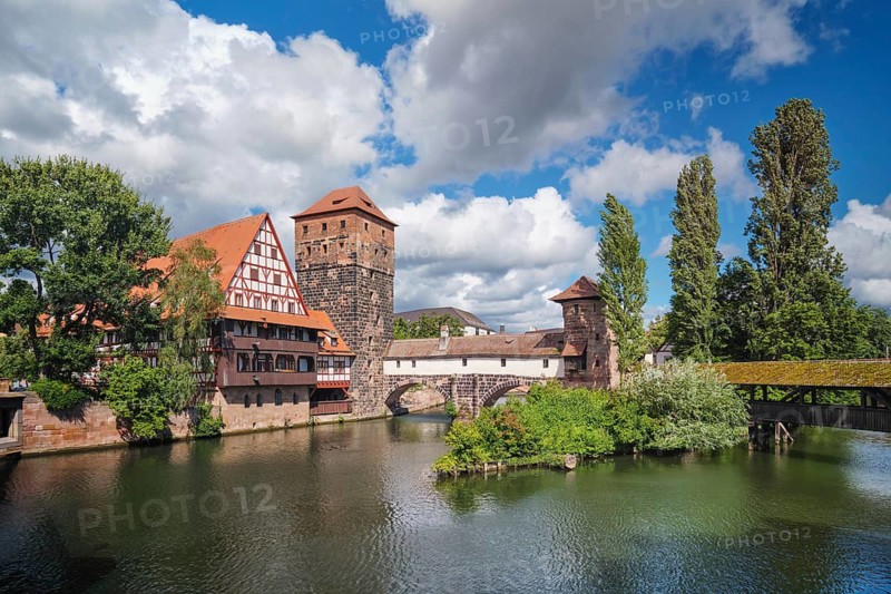 Wide angle view of the medieval riverside architecture in Nuremberg, featuring the Hangman's bridge and Weinstadel under a blue sky