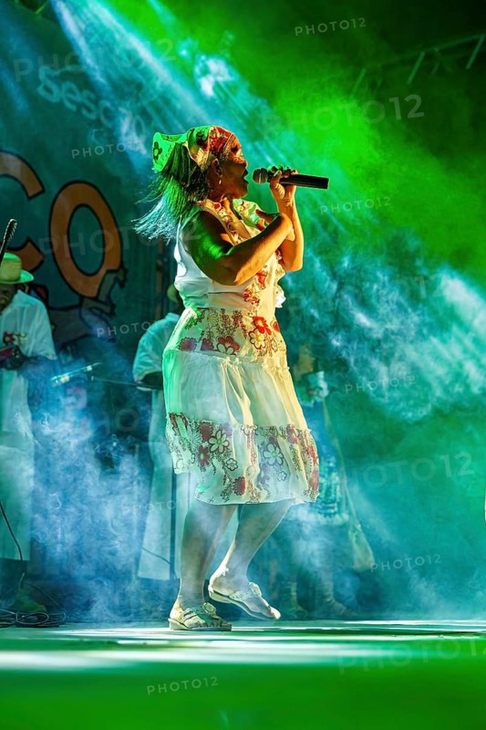 Woman in folklore clothes sings and dances on stage with energy, a band plays and dances at a festival in Petrolina in Brazil