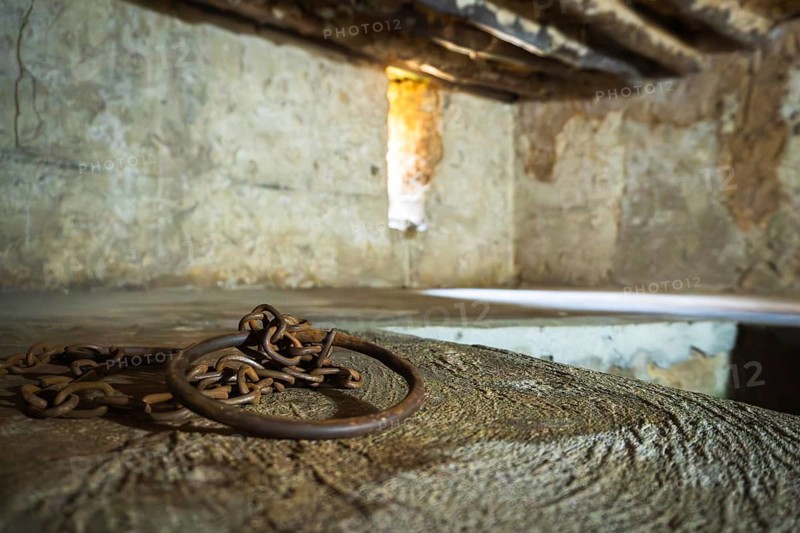 Close-up of authentic iron chains and shackles display in underground slave chamber in Mkunazini, Zanzibar. Somber historic artifact in a dimly lit Stone Town dungeon