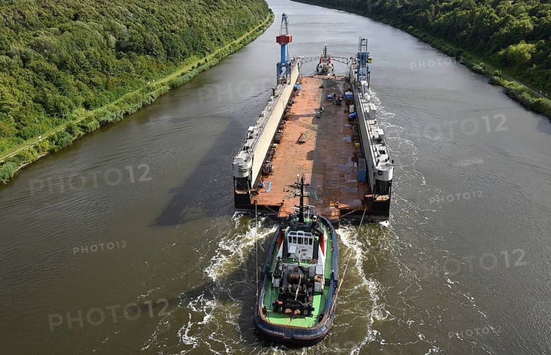 A tugboat pulls a barge on a tree-lined river, tugboat Bremerhaven pulls Dock V through the Kiel Canal, NOK, Kiel Canal, Schleswig-Holstein, Germany