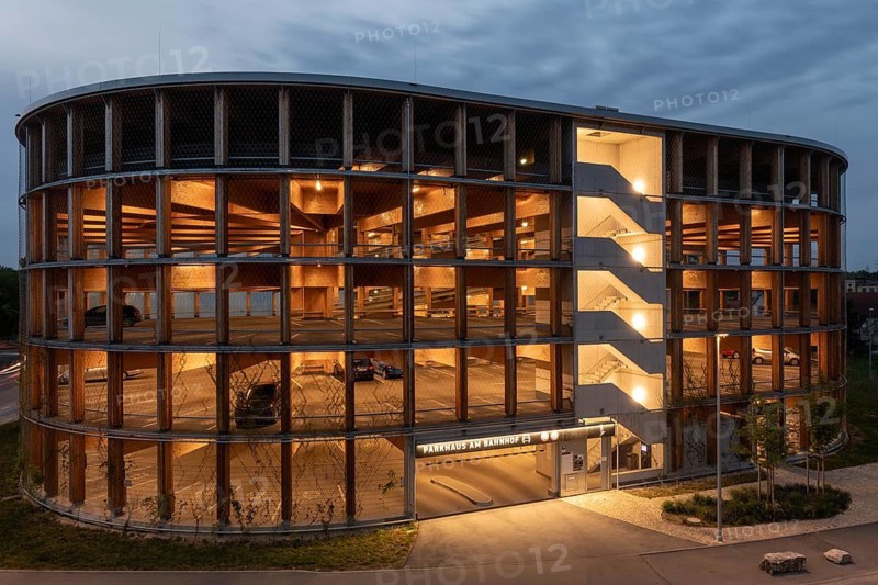 03.05.2026: Illuminated modern timber parking garage (Parkhaus am Bahnhof) with a curved wooden facade at dusk. Wendlingen am Neckar, Baden-Württemberg, Germany