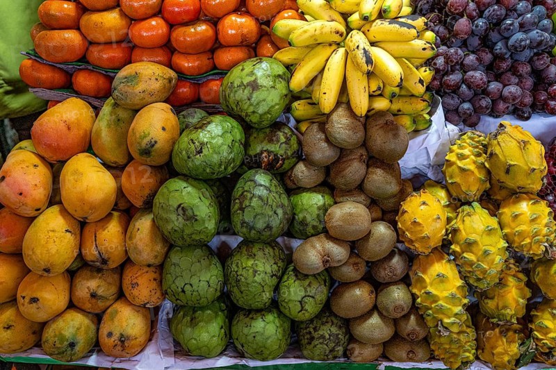 Various exotic fruits, mangoes, cherimoyas, dragon fruit (yellow pitayas), bananas, mandarins and grapes at a stall in a market hall, Arequipa, southern Peru, Peru, South America