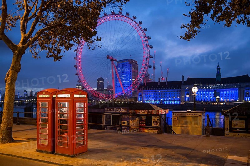 Red K6 style telephone boxes with the London Eye illuminated at dusk, South Bank, London, United Kingdom