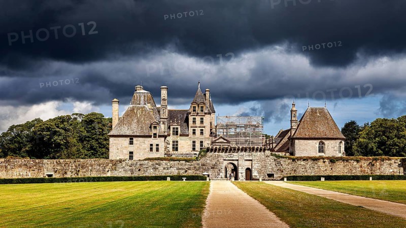 A castle with green lawns and dark skies bathed in dramatic light, The Château de Kerjean Castle in Brittany