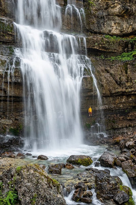 Adventure, Little hiker under large Cascata di Mezzo waterfall, long exposure, Vallesinella, Brenta, Trentino, Italy