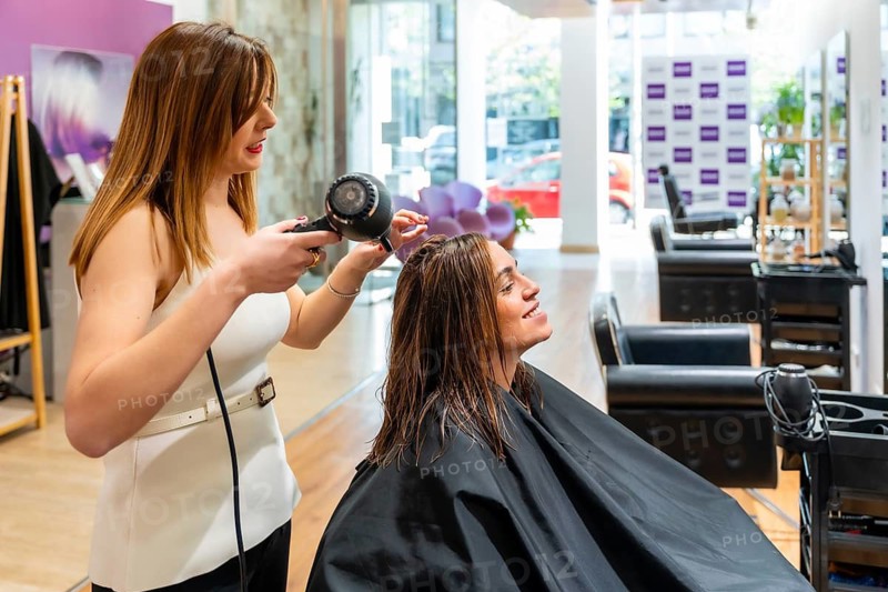 Hairdresser blow drying a smiling womans wet hair in a modern salon, providing professional styling and hair care for a fresh, confident makeover and pampering experience