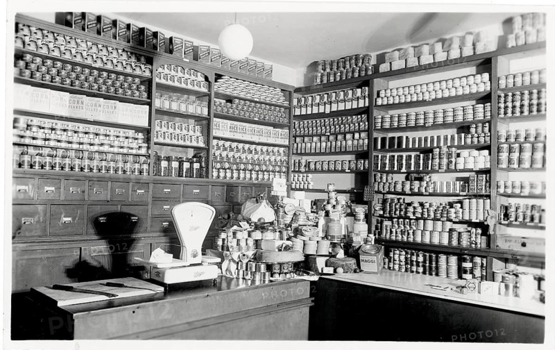 Shop counter, colonial goods, sale, shop, job, twenties, a shop full of shelves with canned goods and a scale on the sales counter, around 1924