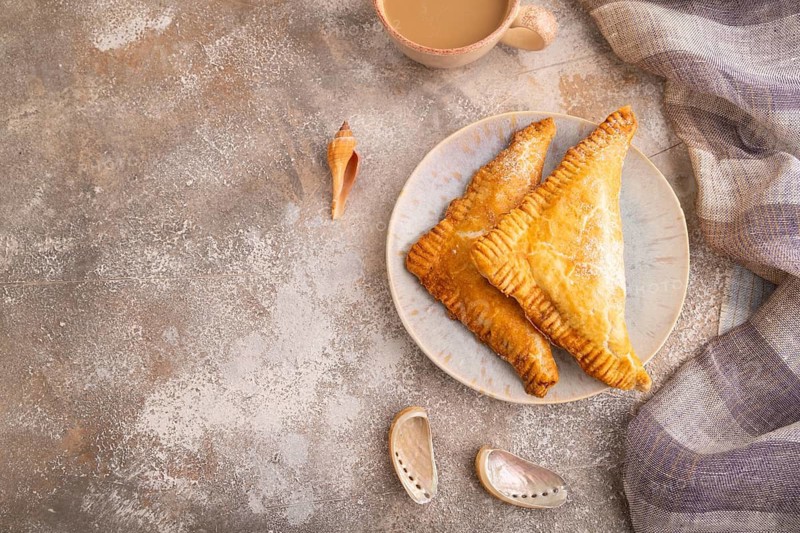 Triangles Pie, Puff Pastry, Samsa with cherry jam on brown concrete background and linen textile, cup of coffee, top view, flat lay, copy space
