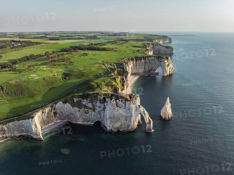 Aerial view of the Porte d'Aval rock formation in the evening sun, well-known sights on the chalk coast with the distinctive rock pin, behind it the La Manneporte rock formation and the Pointe de la Courtine ledge, then Pointe du Fourquet, right on the cliffs the Golf d'Étretat golf course founded in 1908, Alabaster Coast, La Côte d'Albâtre, chalk cliffs, English Channel, Seine-Maritime, Normandie, France