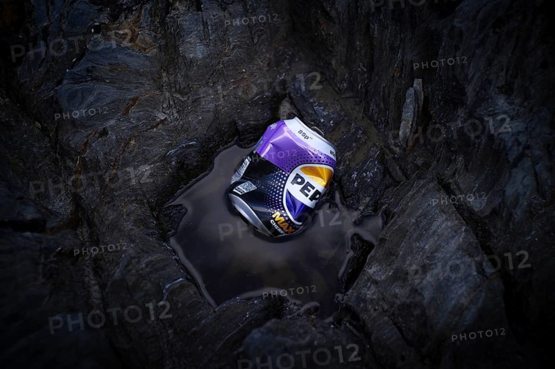 Environmental pollution, trash, empty tin can PEPSI, beverage can, dented, carelessly lying between rocks on the beach, Pennance Point, rocky coast, Falmouth Bay, Cornwall, England, Great Britain, Great Britain
