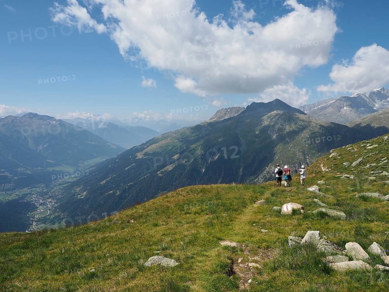 A group of hikers on the mountainside with a wide view of the surrounding peaks and valleys, Bellwald, Goms, Canton of Valais, Switzerland