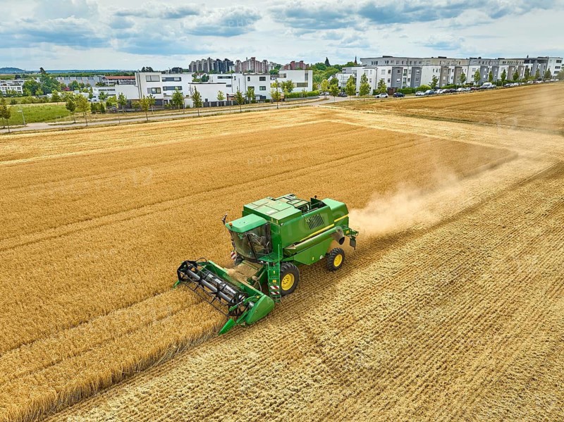 Aireal photo of a combine harvester harvesting wheat on a field in the vertile and fruitful of Langes Feld north of Stuttgart, Baden-Württmberg, Germany