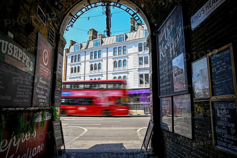 View through the archway of a historic pub onto a passing red double-decker bus, near London Bridge Station, Southwark, London, England, Great Britain, Great Britain