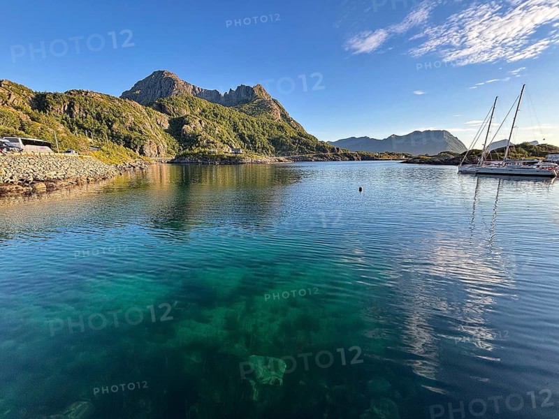Quiet bay with clear blue waters and a sailboat, surrounded by green mountains and clear skies, Hamn, Senja, Troms, Norway