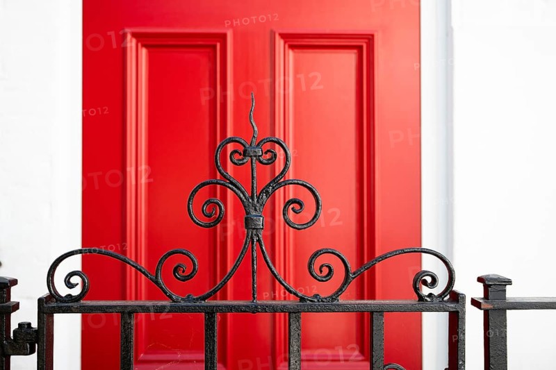Close-up of an elegant curved metal grid in the foreground and red door in the background, Chelsea, London, Great Britain, England, Great Britain