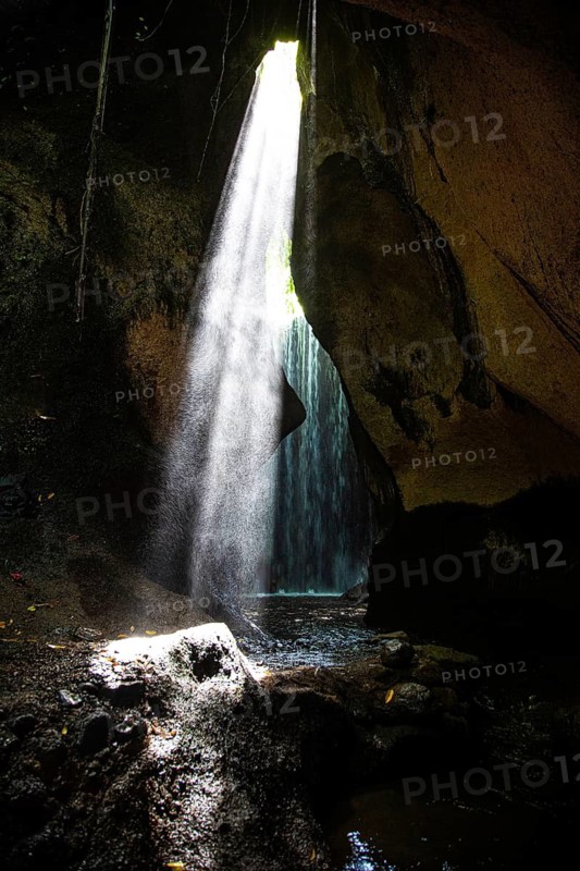 Light beam falls into a dark cave with a waterfall, creates a mysterious atmosphere, Tukad Cepung waterfall, mystical sunlight, Bali, Indonesia