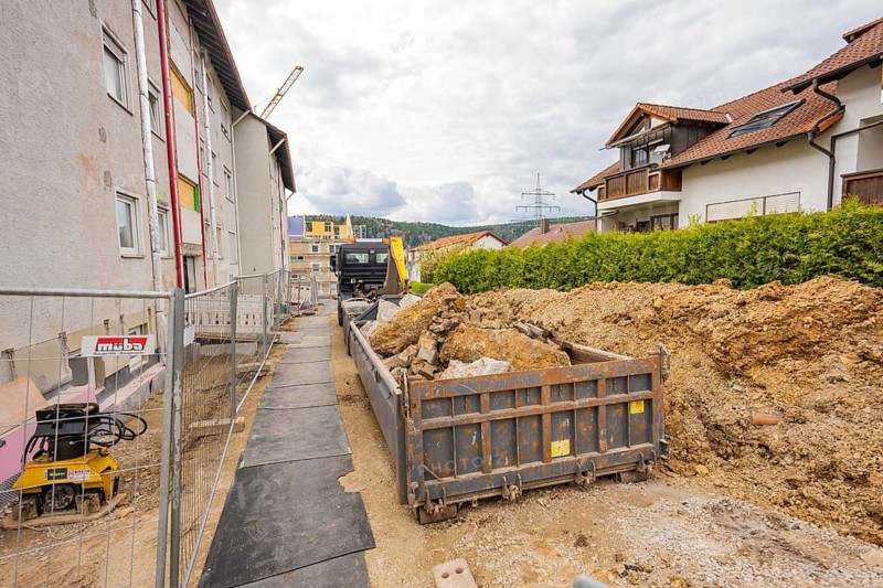 Construction site with containers and building materials in front of a multi-storey residential building and cloudy sky, residential building renovation, Nagold, Calw district, Germany