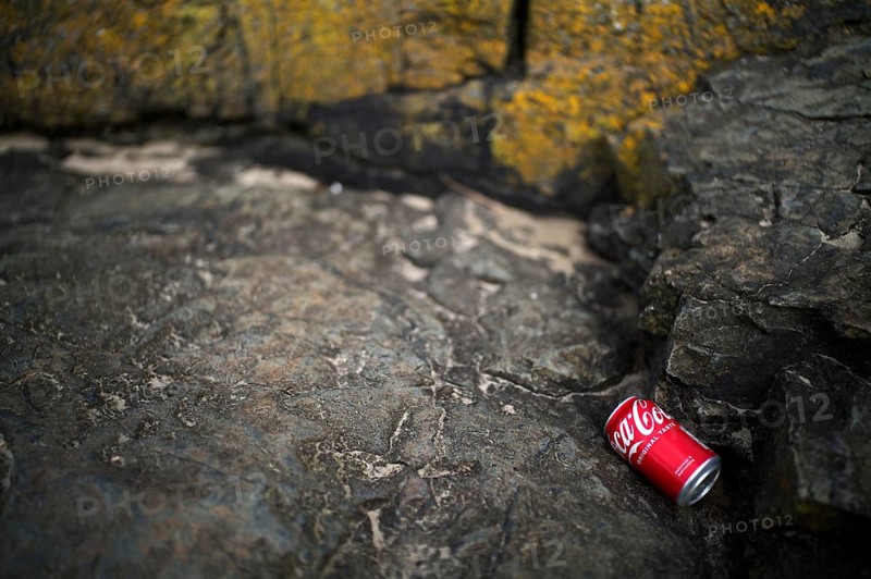 Environmental pollution, empty cola can, Coca Cola, lying on the beach between the rocks, Marazion, Cornwall, England, Great Britain