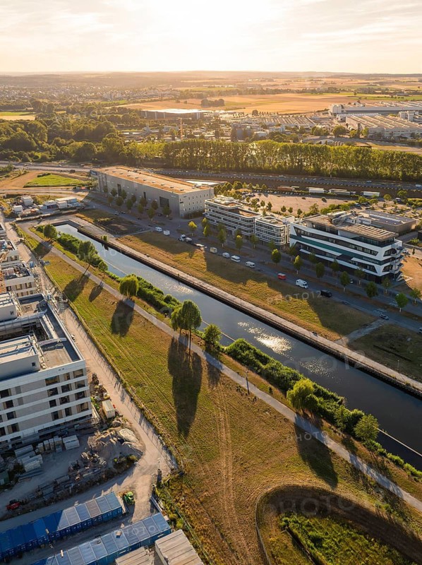 City landscape with canal and buildings at sunset, long shadows falling over green areas, airfield, Böblingen, Germany