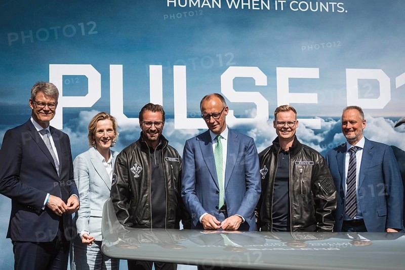 Friedrich Merz between Florian Seibel and Sven Kruck (both from Quantum Systems) at the presentation of the PULS P19 autonomous drone during the Chancellor's tour of the ILA (International Aerospace Exhibition) on 10 June 2026 at the Berlin-Schönefeld Exhibition Centre