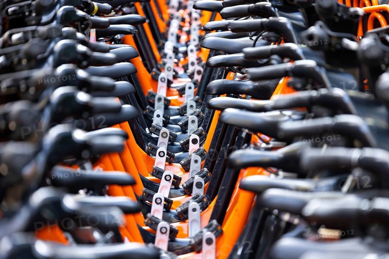 Rows of rental bikes and sharing bicycles parked in the city downtown ready for city commute. Ride sharing