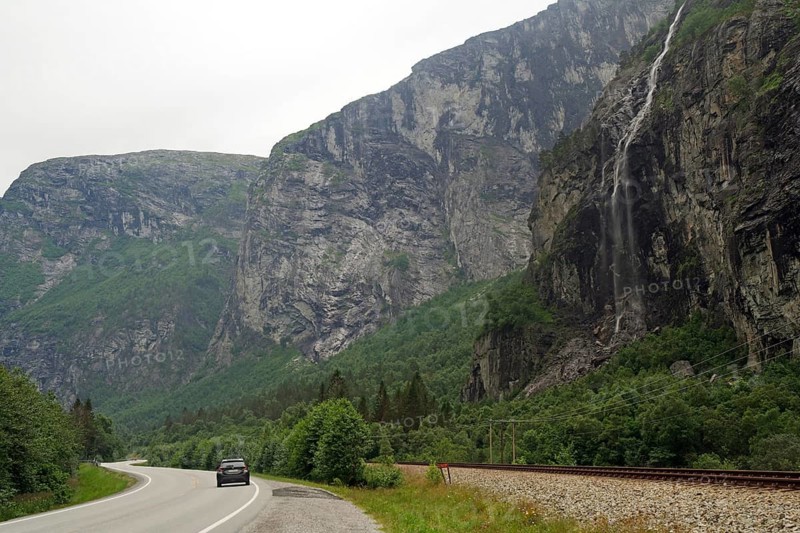 Wet road panorama with waterfall and a car driving down a narrow road, Raumadalen, Trollvegen, Andalsnes, Norway