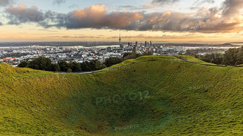 View of city behind the grass crater of the extinct volcano of Mount Eden, Auckland, New Zealand