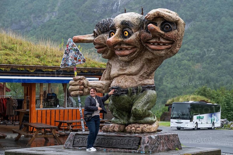 Sculpture of an oversized troll with three heads holding a sticker road sign, coach in the background, Trollstigen Camping, near Åndalsnes or Andalsnes, Rauma municipality in the province of Møre og Romsdal, Norway
