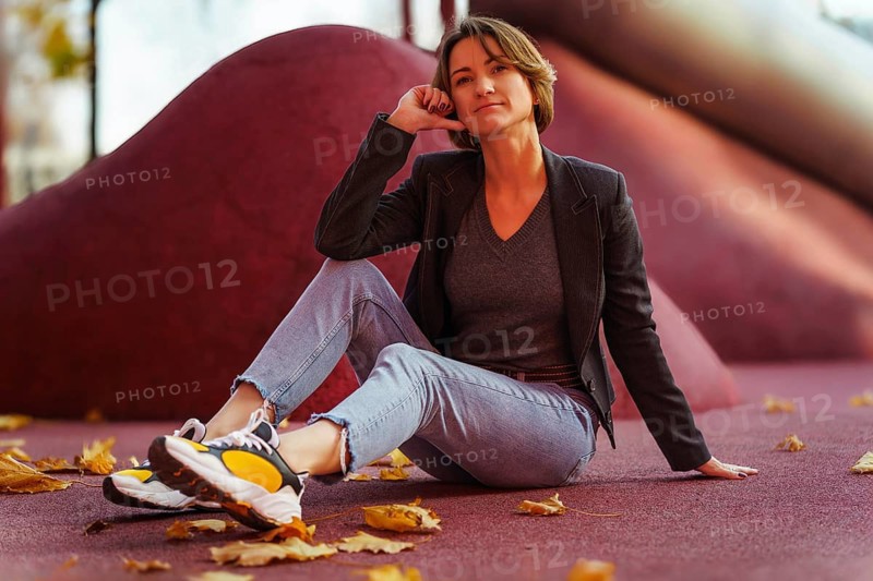 Young woman enjoying autumn leaves on red background