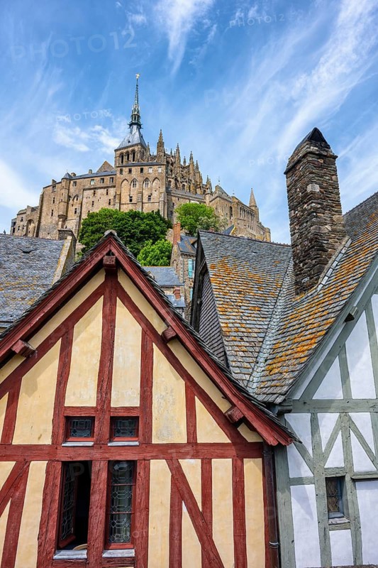 Medieval alley and traditional half-timbered houses within the fortress walls of Mont-Saint-Michel. In the background rises the famous Benedictine monastery, tourist attraction, UNESCO World Heritage Site, Pontorson, Manche department, Normandy, France